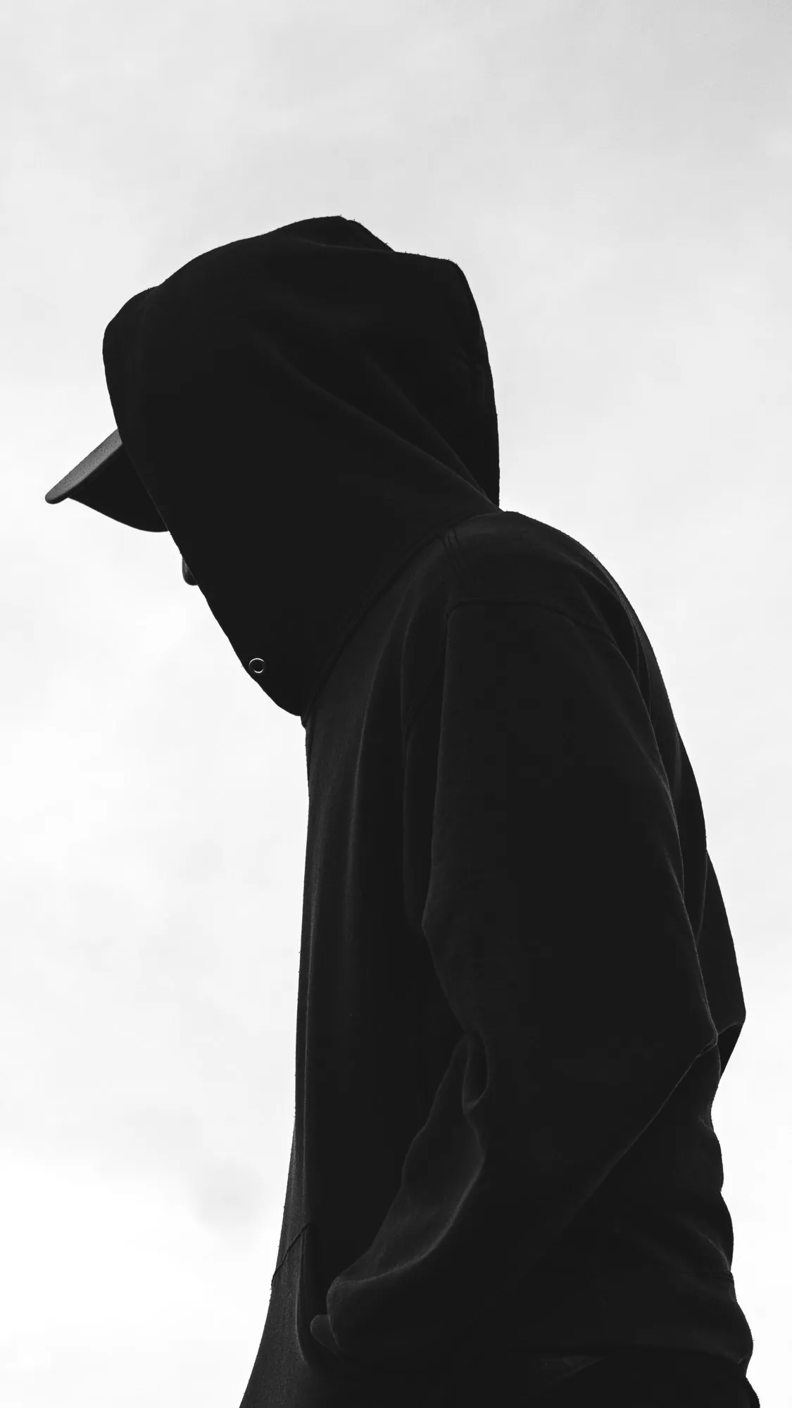 Sin1Rostro de capucha y gorra contra el cielo